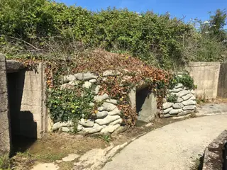 Antigos paióis ainda protegidos por sacos de areia na bateria costeira de Maisy